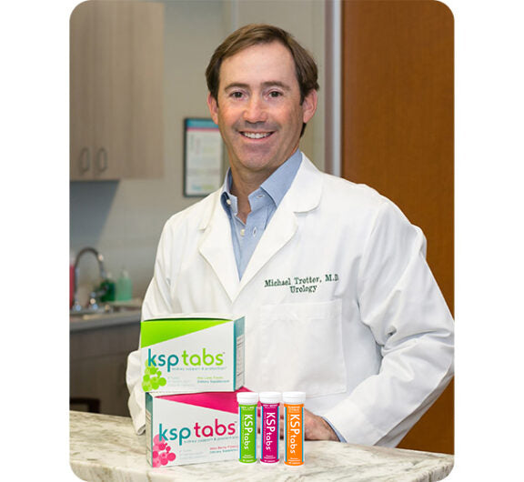 Man in a white lab coat holding boxes of ksptabs products in a medical setting.